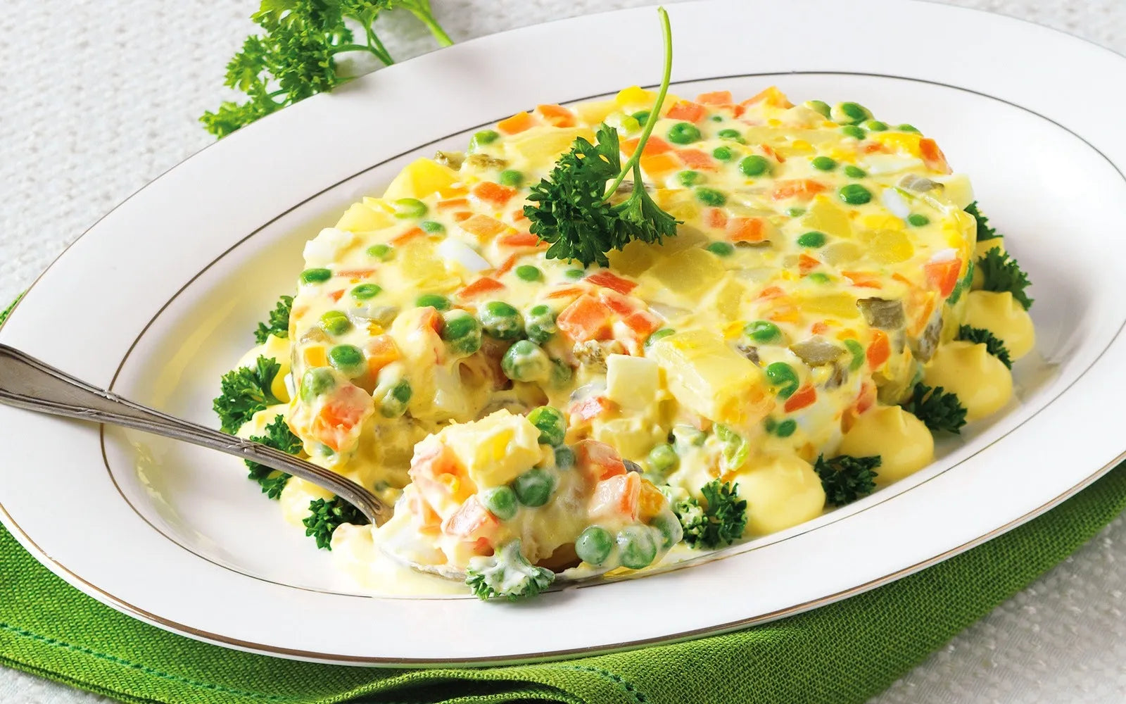 Insalata russa classique servie dans un bol décoré avec de la mayonnaise.