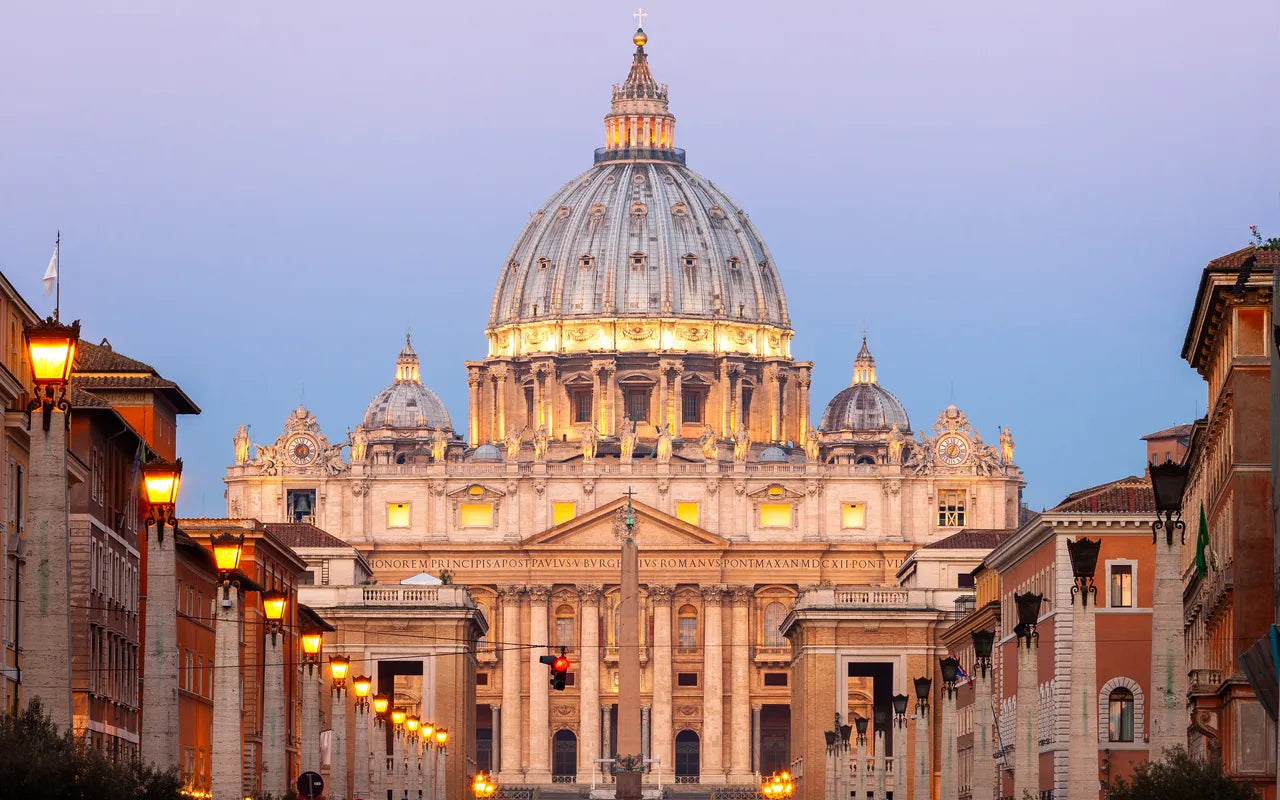 Vue iconique de la basilique Saint-Pierre illuminée au crépuscule, idéale pour illustrer un article sur où manger près du Vatican, les restaurants autour de la basilique ou les meilleurs cafés du quartier.
