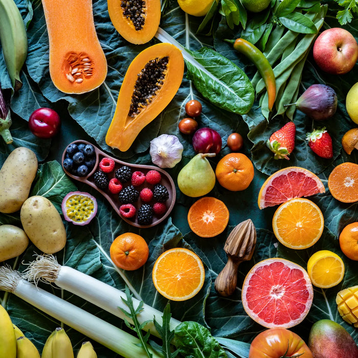 Fruits et légumes colorés étalés sur des feuilles vertes, symbolisant une alimentation équilibrée face à la diète cétogène