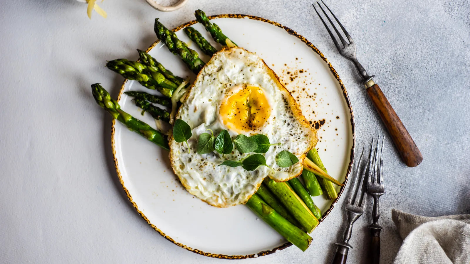 Assiette d'asperges poêlées accompagnées d'un œuf au plat sur un lit de mâche