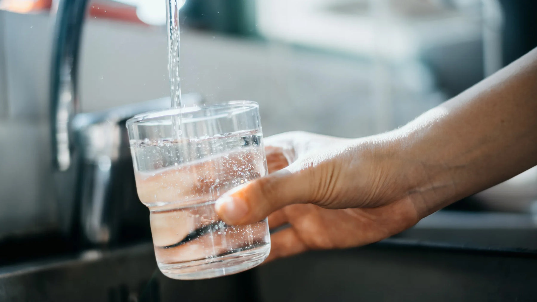 Verre d’eau du robinet rempli à l’évier – symbole d’eau potable contrôlée et sûre à domicile