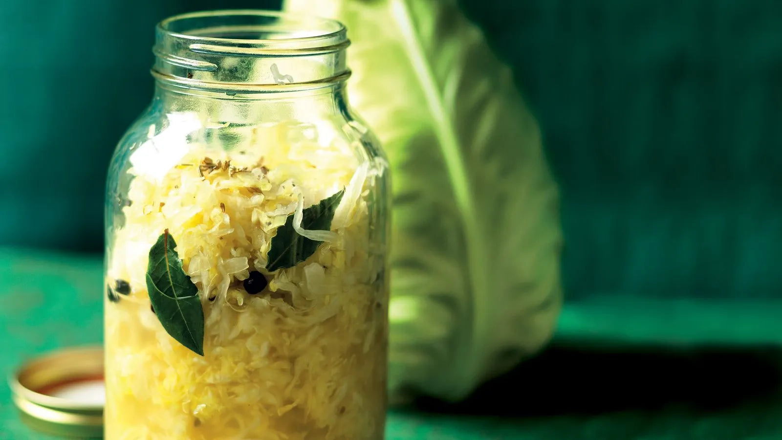 Chou fermenté fait maison dans un bocal en verre avec feuilles de laurier et baies de genièvre – aliment fermenté riche en probiotiques