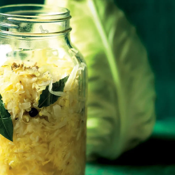 Chou fermenté fait maison dans un bocal en verre avec feuilles de laurier et baies de genièvre – aliment fermenté riche en probiotiques