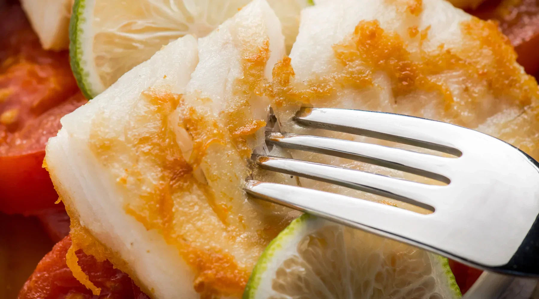 Filet de poisson blanc délicatement doré, accompagné de rondelles de citron vert et de tomates, un plat sain et savoureux idéal pour la période de Carême.