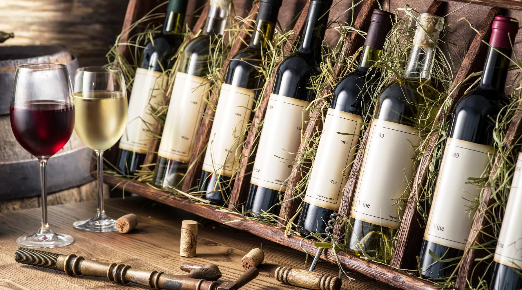 Coffret de bouteilles de vin rouge et blanc millésimé 1989 avec deux verres de dégustation, sur table en bois avec bouchons et accessoires d’œnologue
