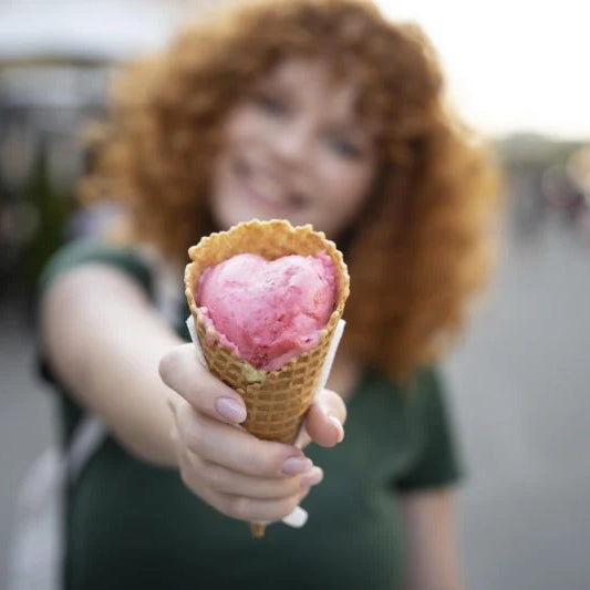 Femme souriante tenant un cornet de glace rose en forme de cœur pendant la Gelato Week 2025 en Italie
