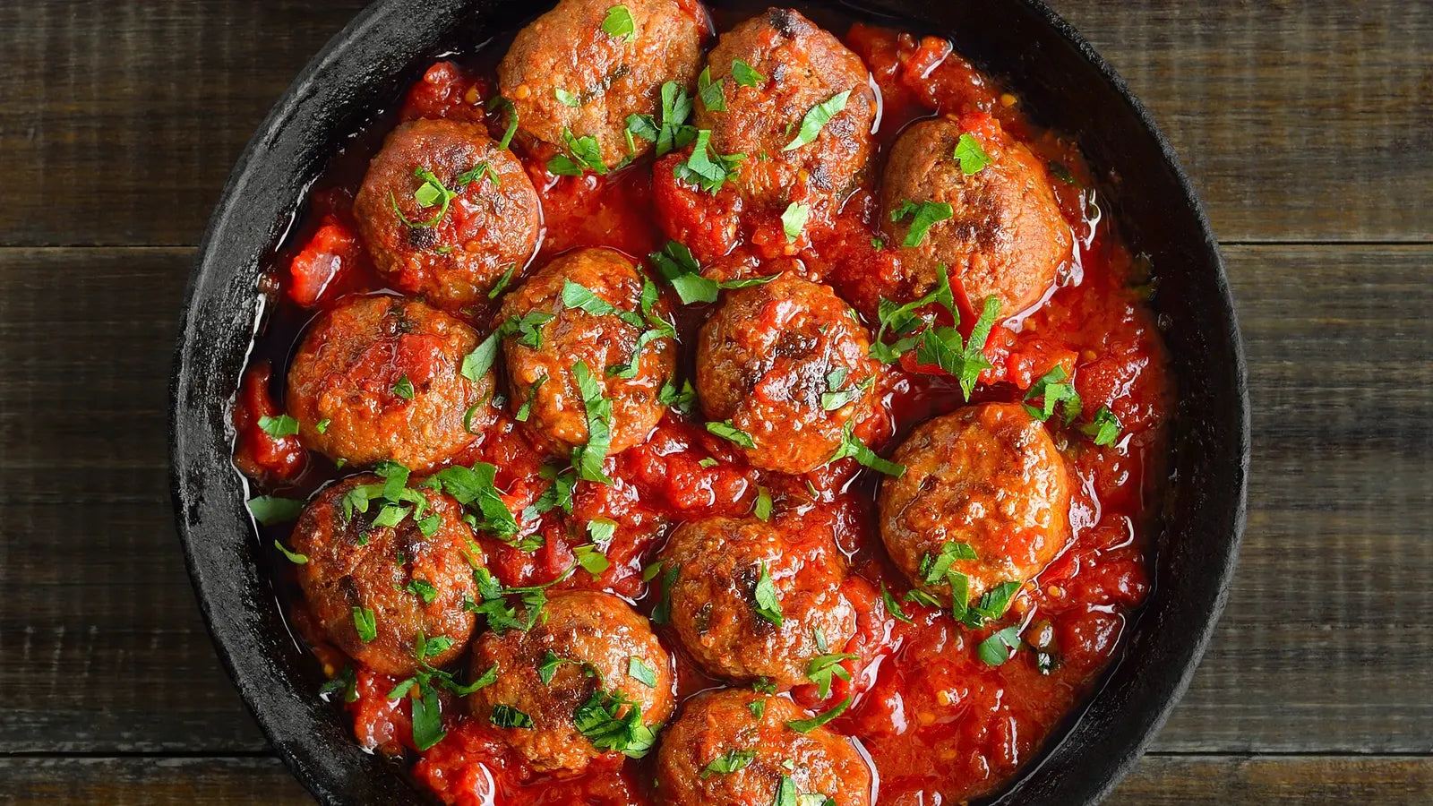 Boulettes végétariennes de pois chiches dans une sauce tomate maison, servies dans une poêle noire