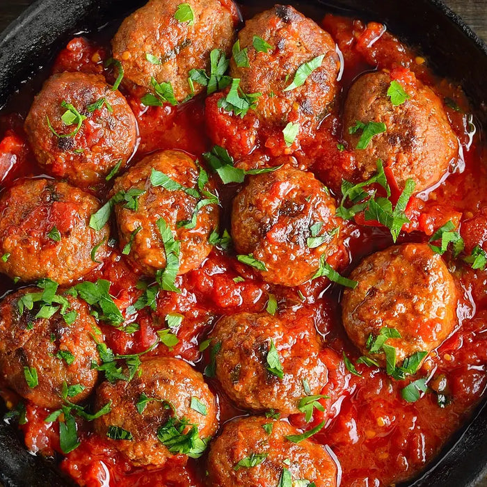 Boulettes végétariennes de pois chiches dans une sauce tomate maison, servies dans une poêle noire