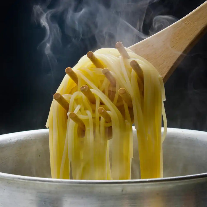 Cuisson des pâtes dans une casserole avec des spaghetti soulevés à la cuillère en bois