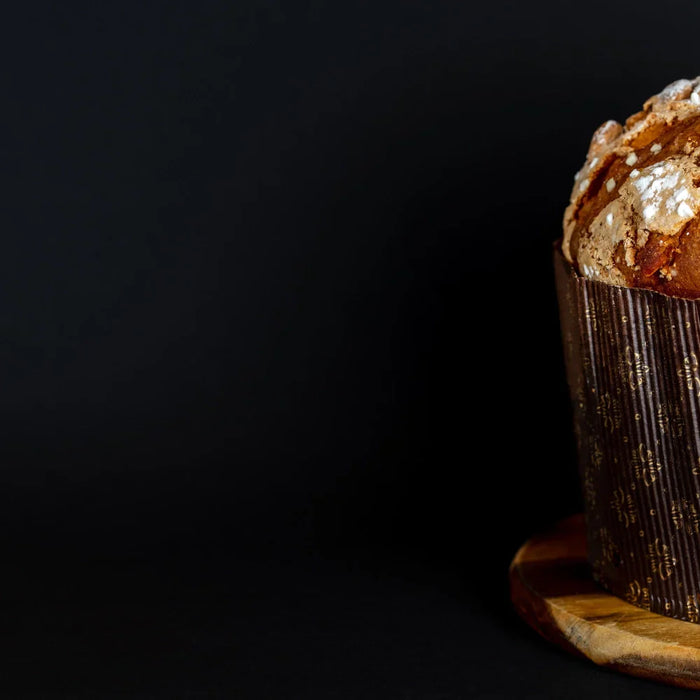 Panettone artisanal italien sur fond noir, brioche traditionnelle de Noël avec croûte dorée et sucre perlé