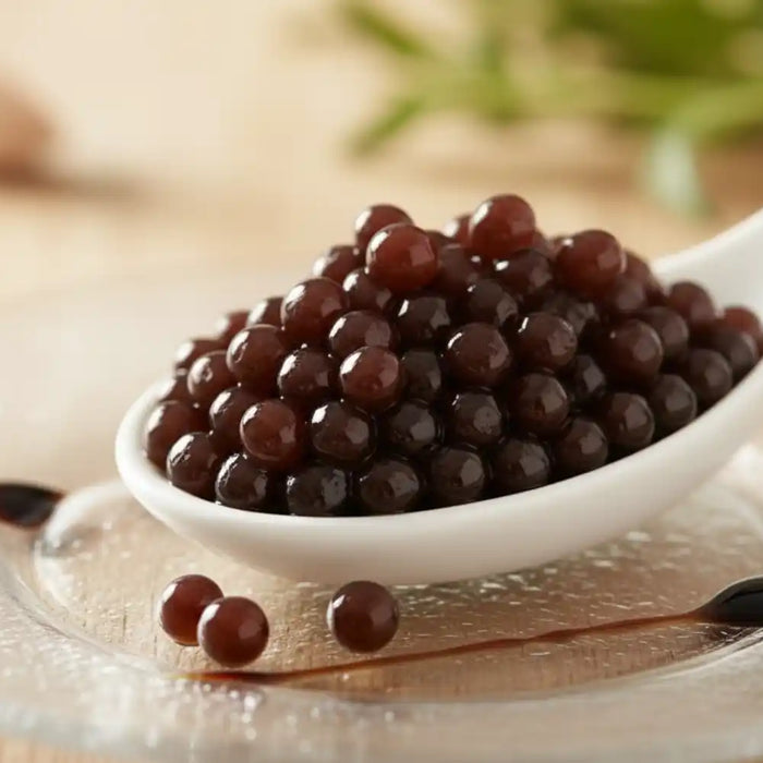 Perles de vinaigre balsamique dans une cuillère blanche sur assiette transparente
