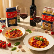 Italienisches Premium-Dinner mit Di Martino-Pasta, Sole e Napule-Tomaten und Primitivo-Wein, serviert mit zwei Tellern Pasta al Pomodoro.